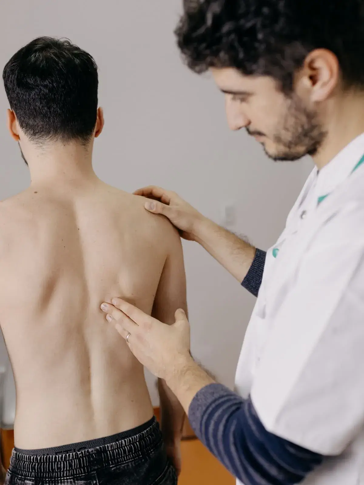 Medic specialist medicina fizica si reabilitare, Dr. Danut Perja, examinând spatele unui pacient pentru diagnosticare în cadrul recuperării medicale.